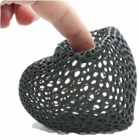 Favism3D: Impresión 3D con resinas flexibles para prototipos elásticos, componentes de absorción y piezas funcionales. Dedo presionando una pieza impresa en 3D con resina flexible de patrón Voronoi, mostrando su elasticidad.